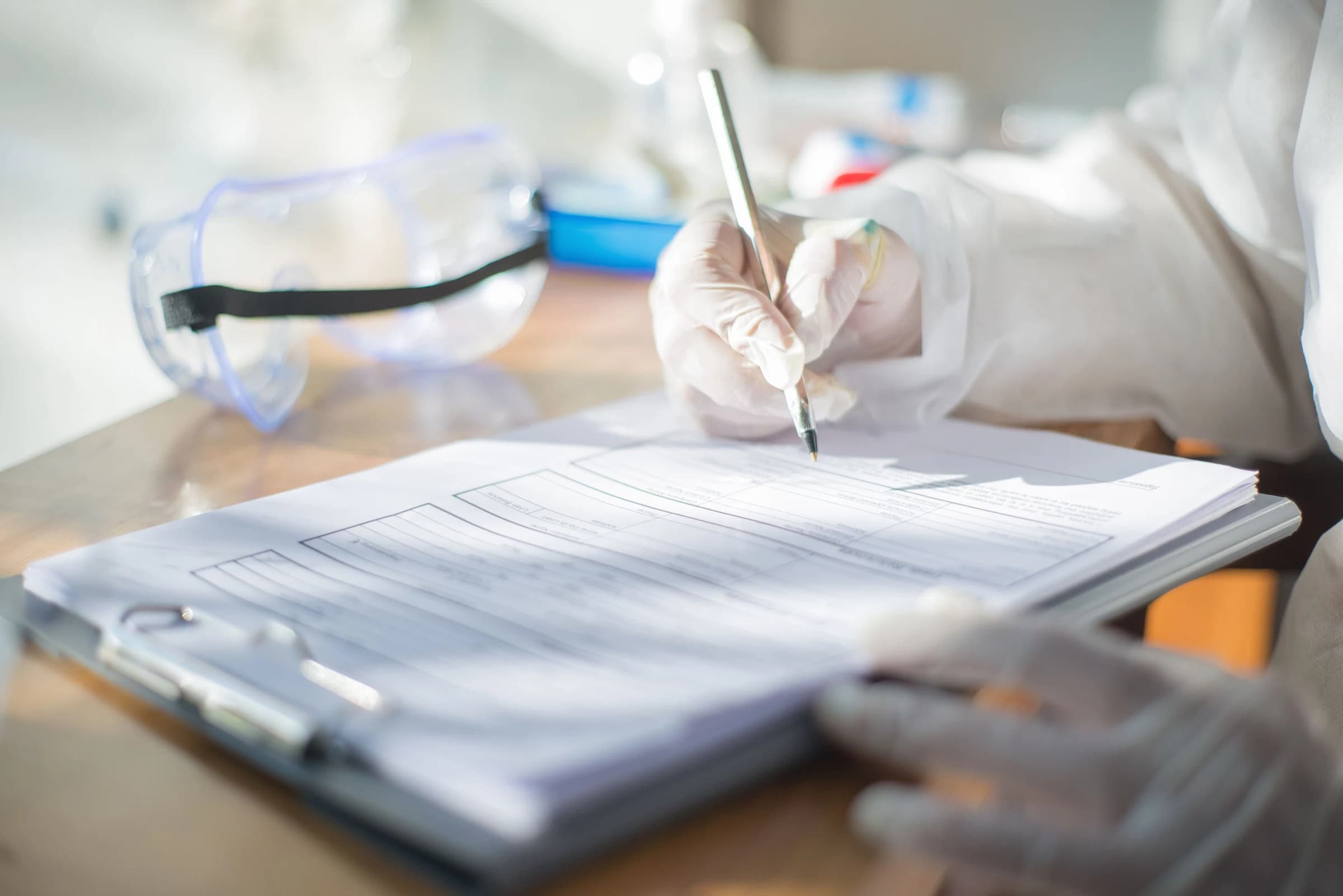 Gloved hands recording notes on a technical document in a laboratory